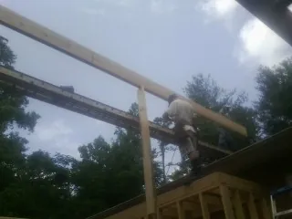 Carpenter setting a ridge beam over a new addition frame — Ice Dam Removal by Roofing Brothers in Bay Saint Louis
