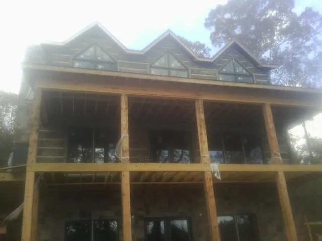 Dormers and porch framing on a large log home under construction — Roof Coating work by our crew in Bay Saint Louis