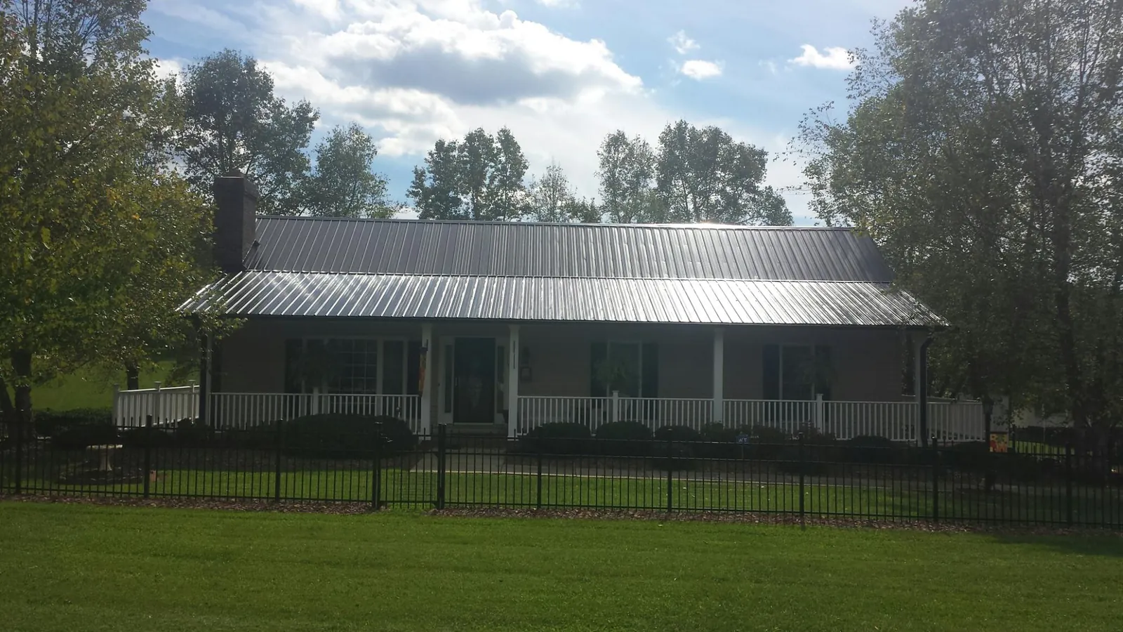 Gray metal roof on a brick ranch with a full width front porch — Gutter Guard Installation work by our crew in Bay Saint Louis