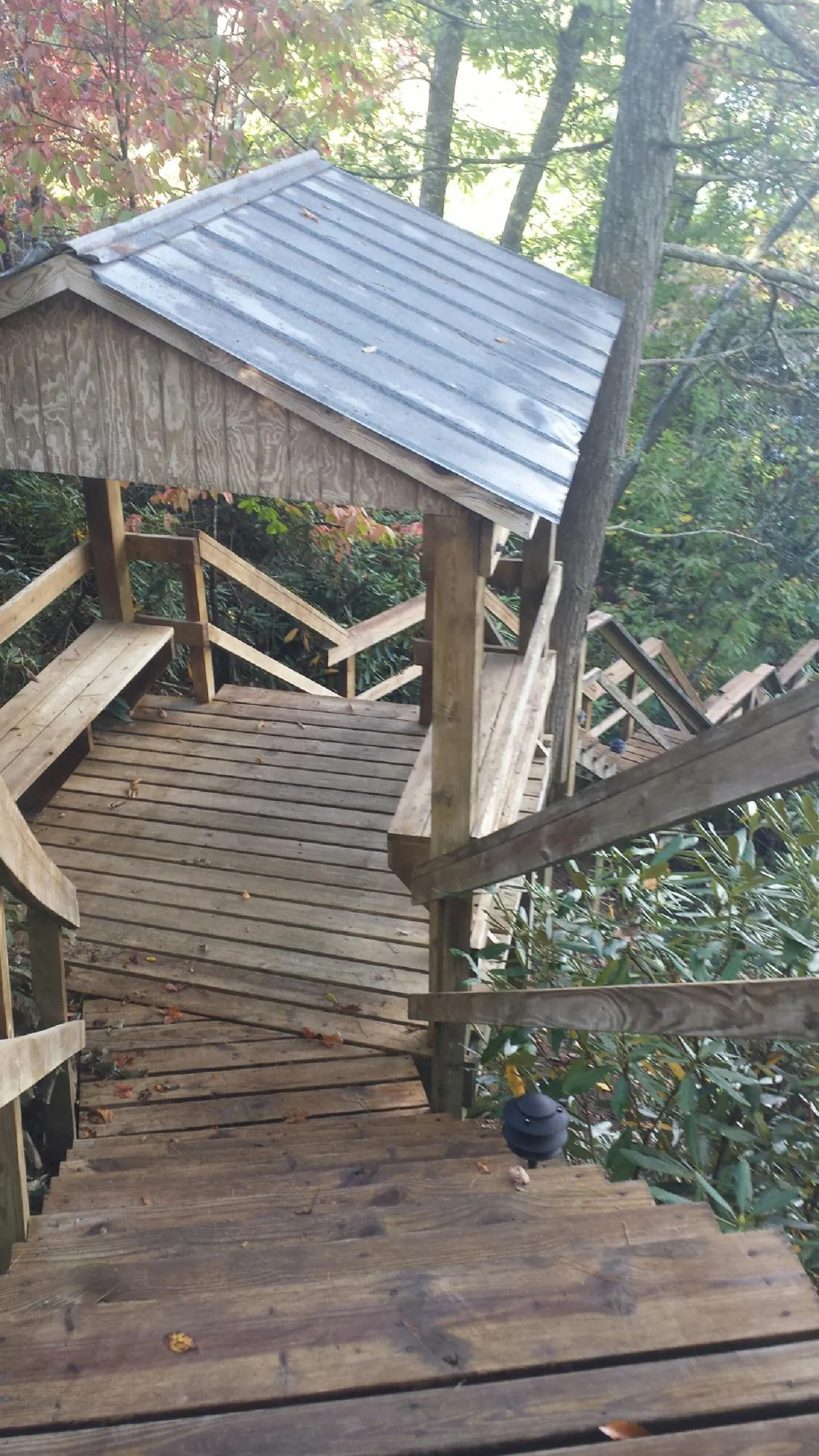 Metal roofed shelter over wooden steps on a wooded walkway — Skylight Repair & Installation work by our crew in Bay Saint Louis